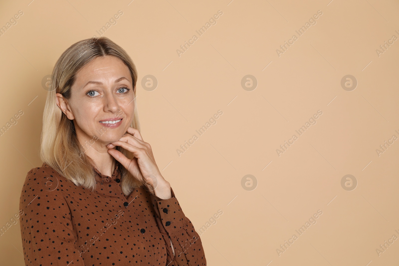 Photo of Portrait of beautiful smiling woman on beige background, space for text