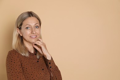 Portrait of beautiful smiling woman on beige background, space for text