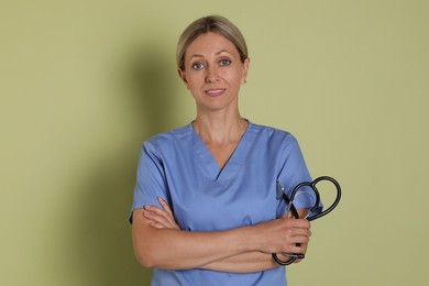 Photo of Portrait of nurse in medical uniform with stethoscope on light green background