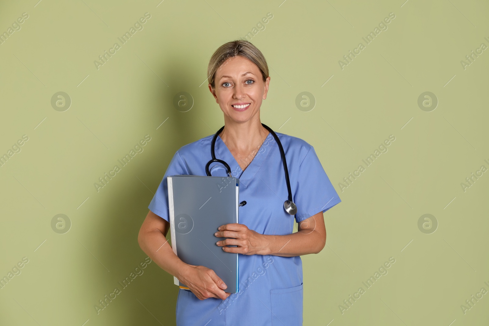 Photo of Portrait of nurse in medical uniform with folders on light green background