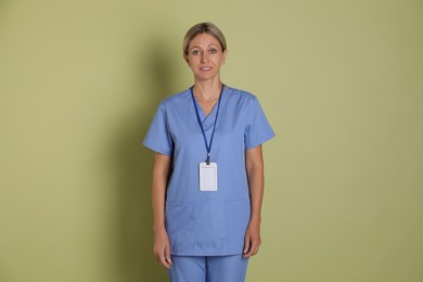 Photo of Portrait of nurse in medical uniform with badge on light green background