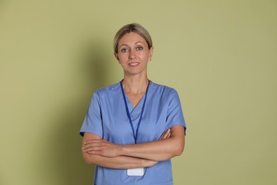 Portrait of nurse in medical uniform with badge on light green background