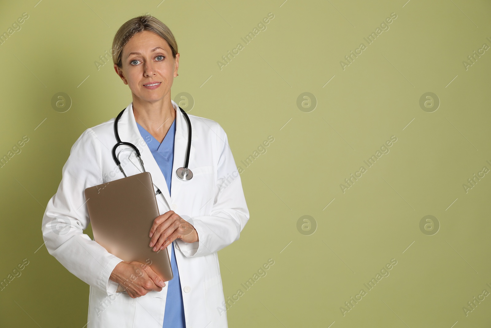 Photo of Doctor in medical uniform with stethoscope and laptop on light green background, space for text