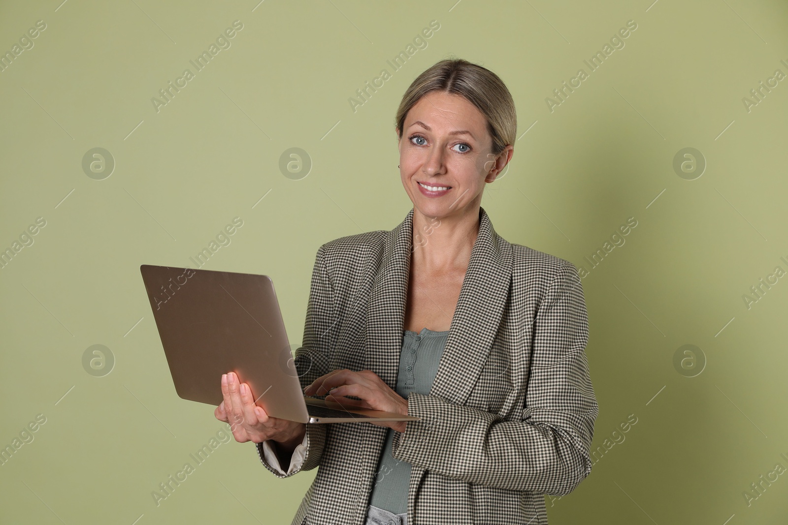 Photo of Portrait of beautiful smiling woman with laptop on olive background