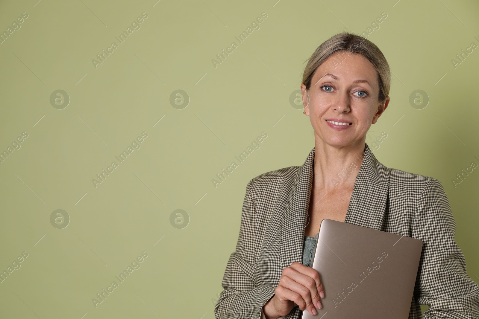 Photo of Portrait of beautiful smiling woman with laptop on olive background, space for text