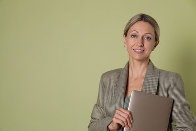 Portrait of beautiful smiling woman with laptop on olive background, space for text