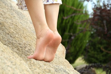 Photo of Woman standing barefoot on rock outdoors, closeup. Space for text