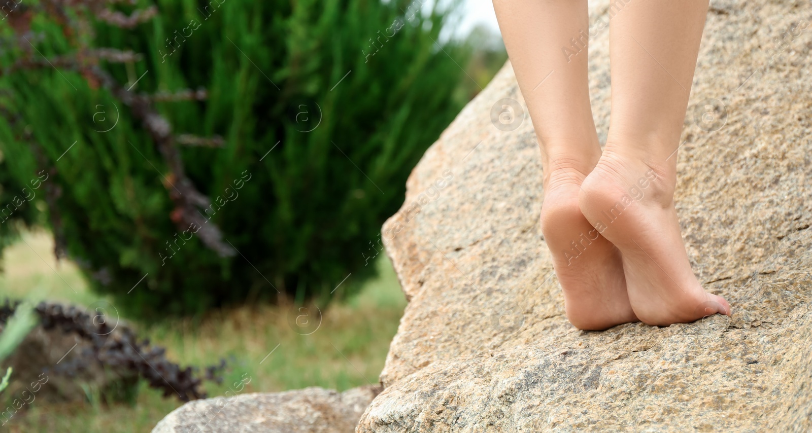 Photo of Woman standing barefoot on rock outdoors, closeup. Space for text