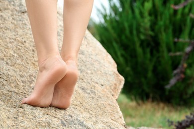 Photo of Woman standing barefoot on rock outdoors, closeup. Space for text