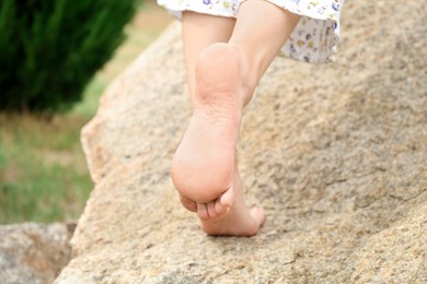 Photo of Woman standing barefoot on rock outdoors, closeup