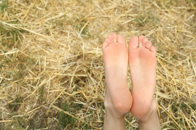 Photo of Woman lying barefoot on straw outdoors, closeup. Space for text