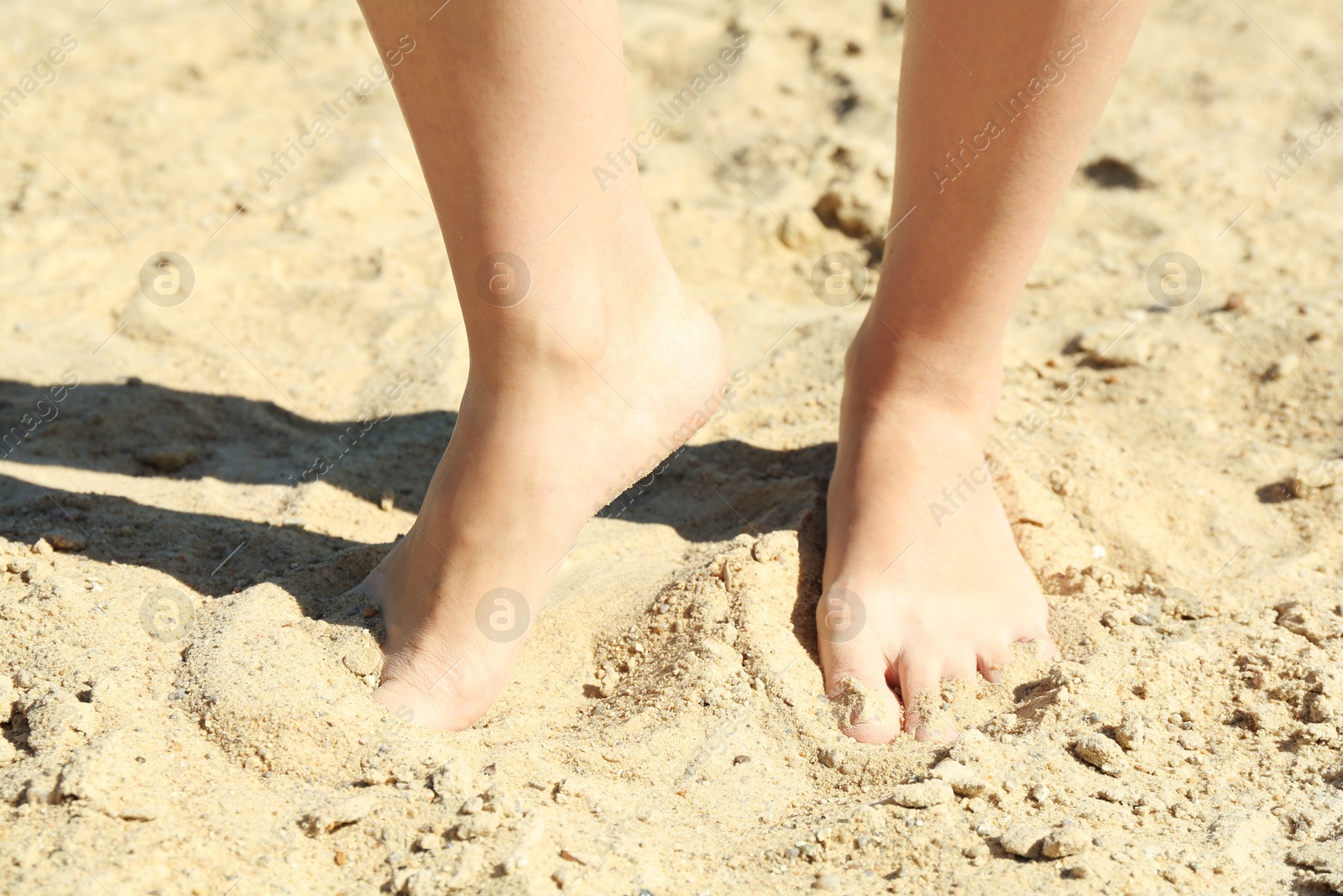 Photo of Woman standing barefoot on sand outdoors, closeup