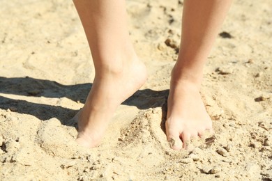 Photo of Woman standing barefoot on sand outdoors, closeup