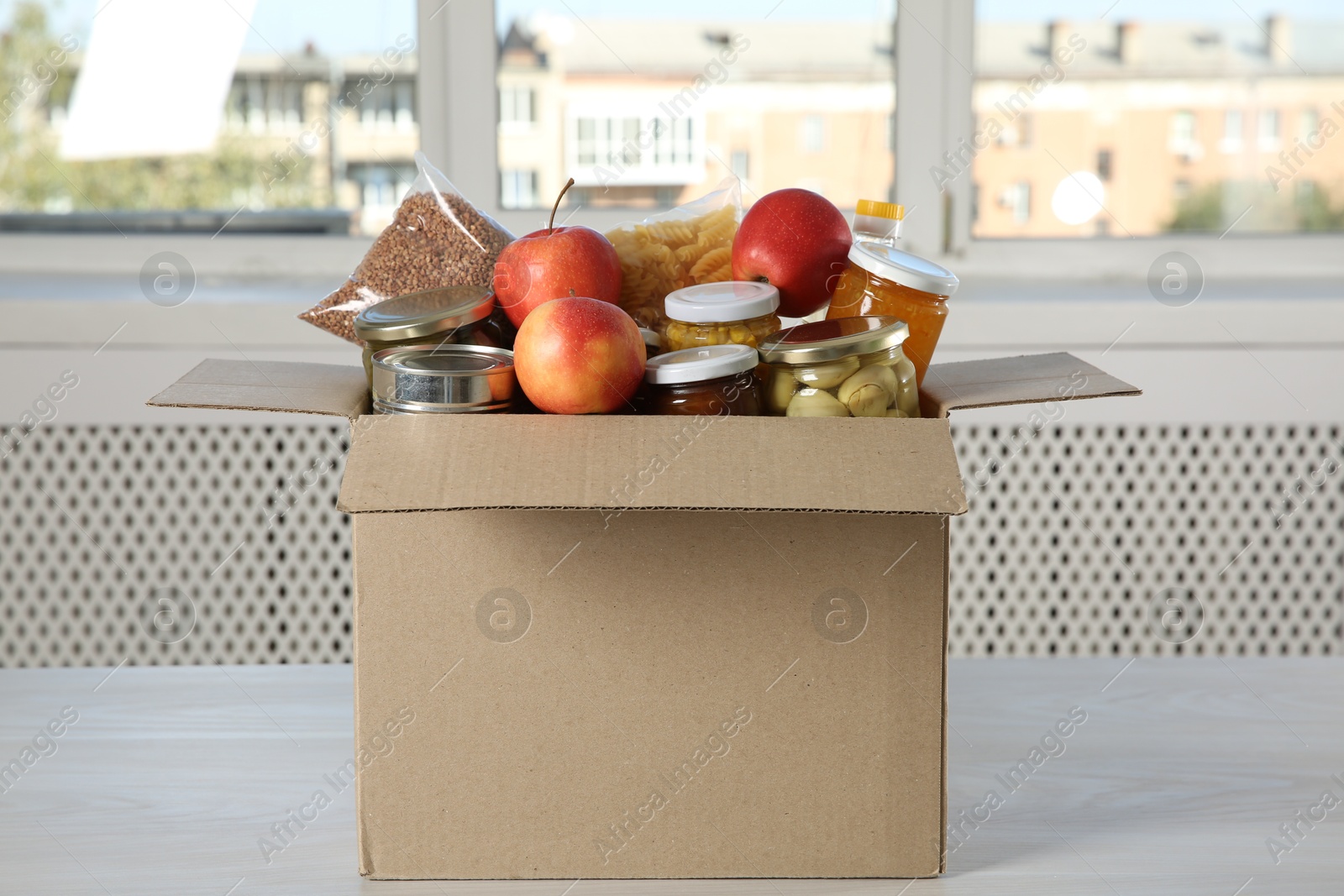 Photo of Different food products for donation in box on wooden table indoors