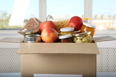 Photo of Different food products for donation in box indoors, closeup