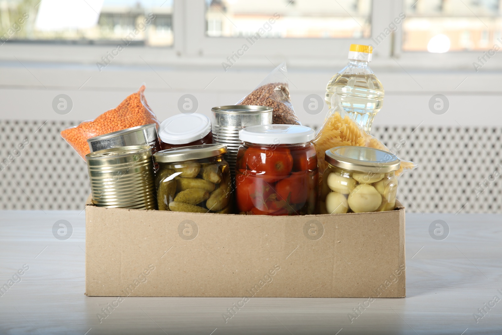 Photo of Different food products for donation in box on wooden table indoors