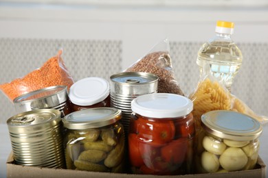 Photo of Different food products for donation in box indoors, closeup