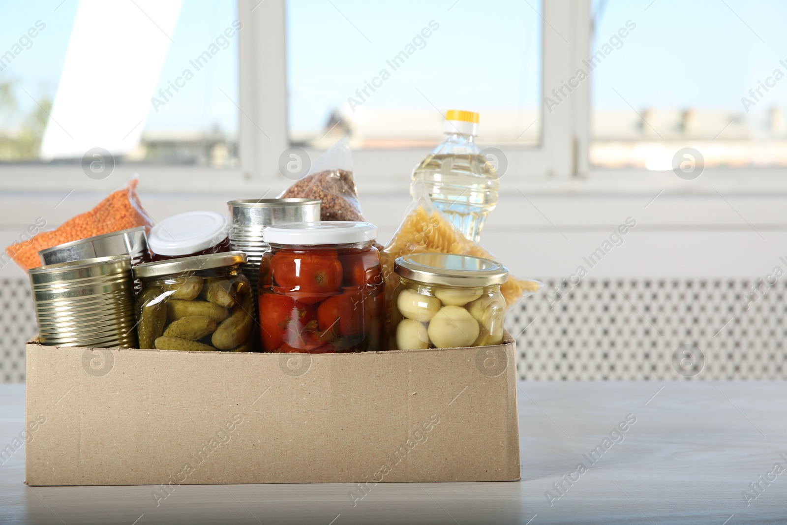 Photo of Different food products for donation in box on wooden table indoors