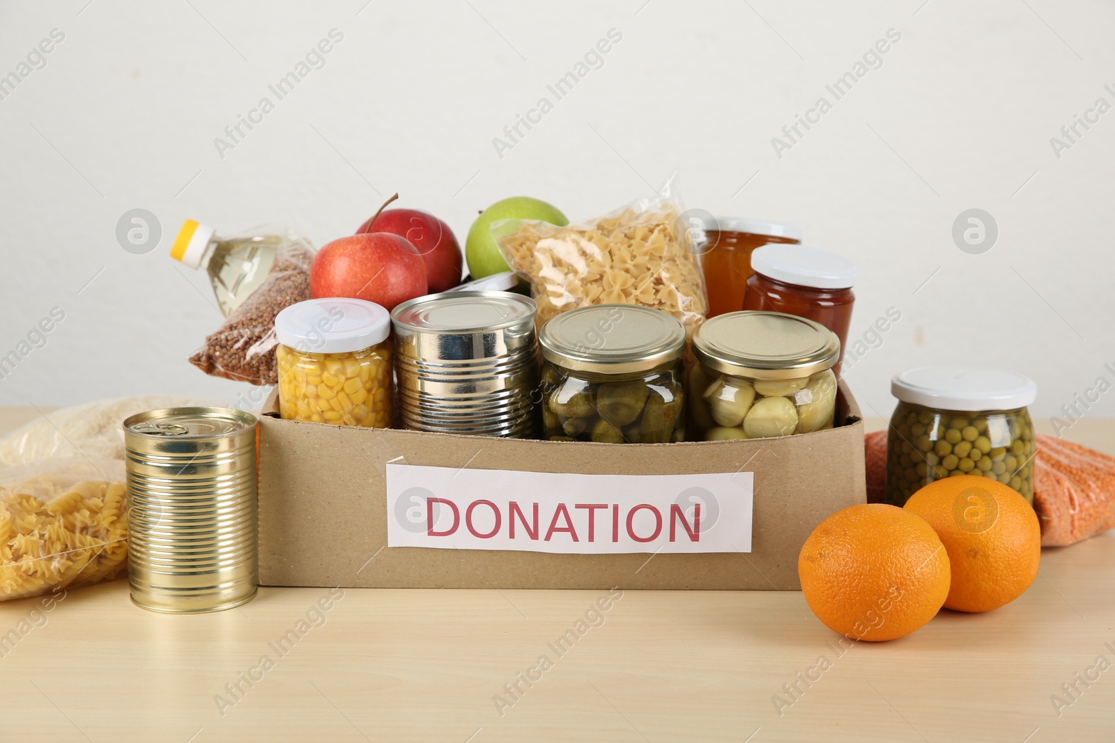 Photo of Different food products for donation in box on wooden table indoors