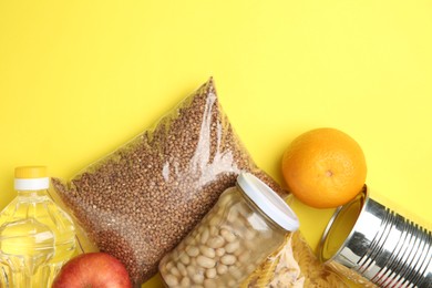 Photo of Food donation. Different products on yellow background, flat lay. Space for text