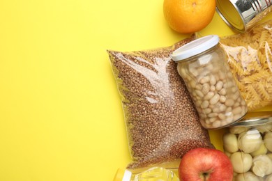 Photo of Food donation. Different products on yellow background, flat lay. Space for text