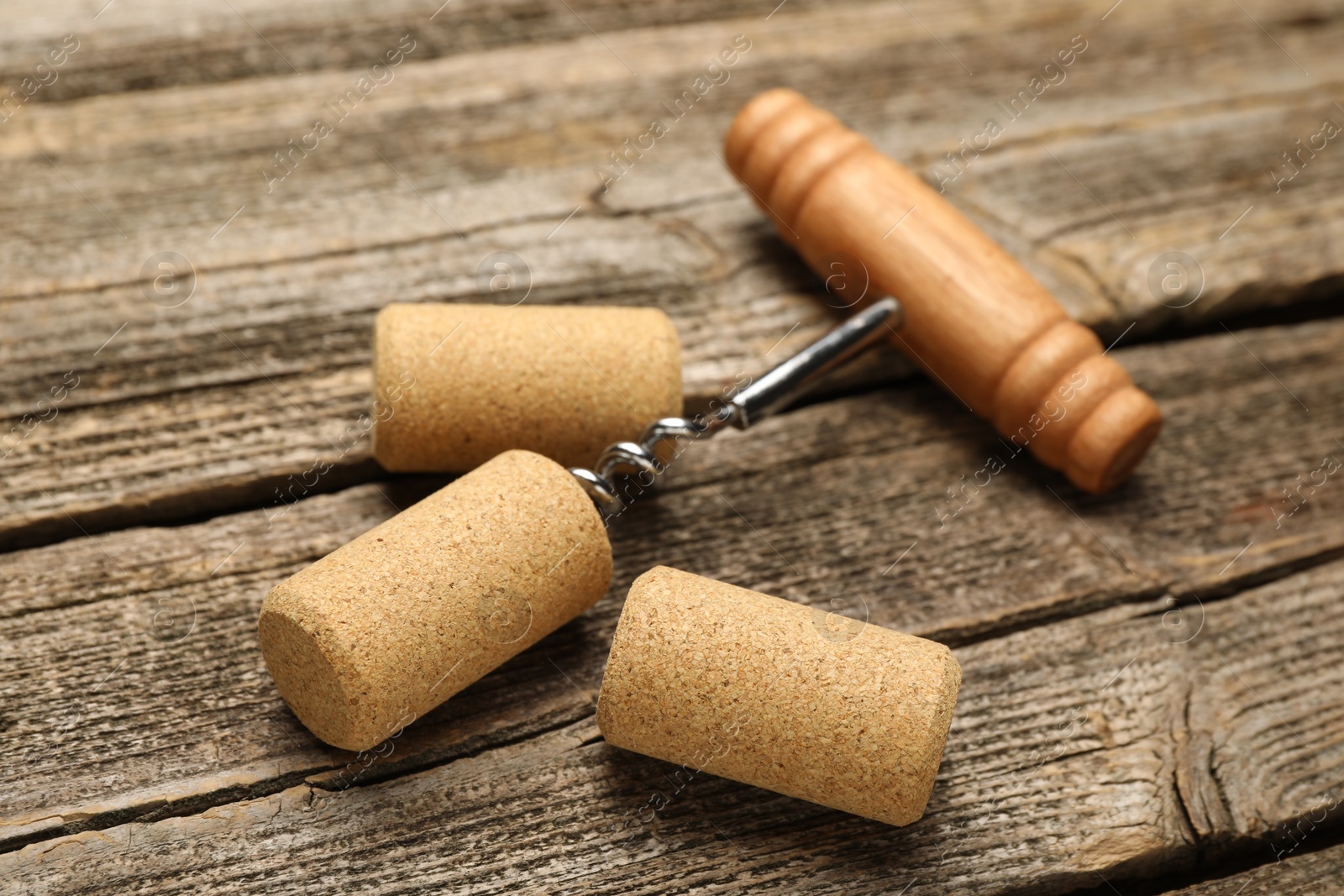 Photo of Corkscrew with handle and corks on wooden table