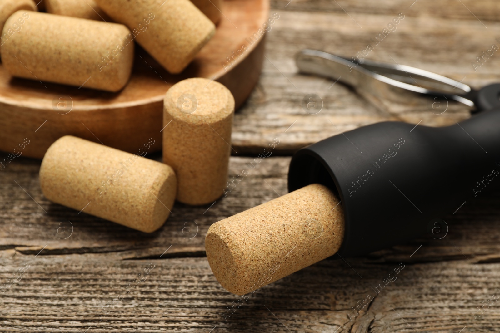 Photo of Wing corkscrew and corks on wooden table, closeup