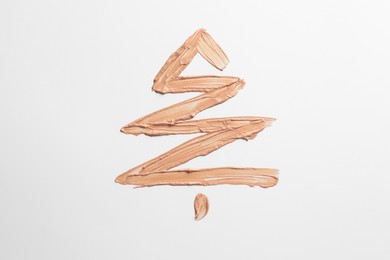 Christmas tree made of skin foundation on white background, top view