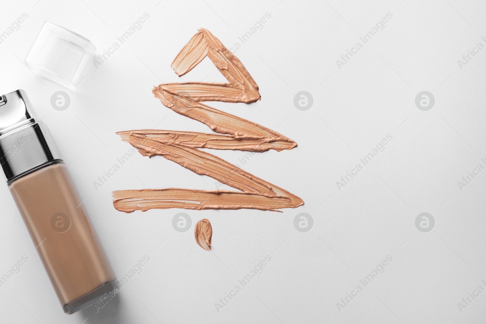 Photo of Christmas tree made of skin foundation and bottle on white background, top view. Space for text