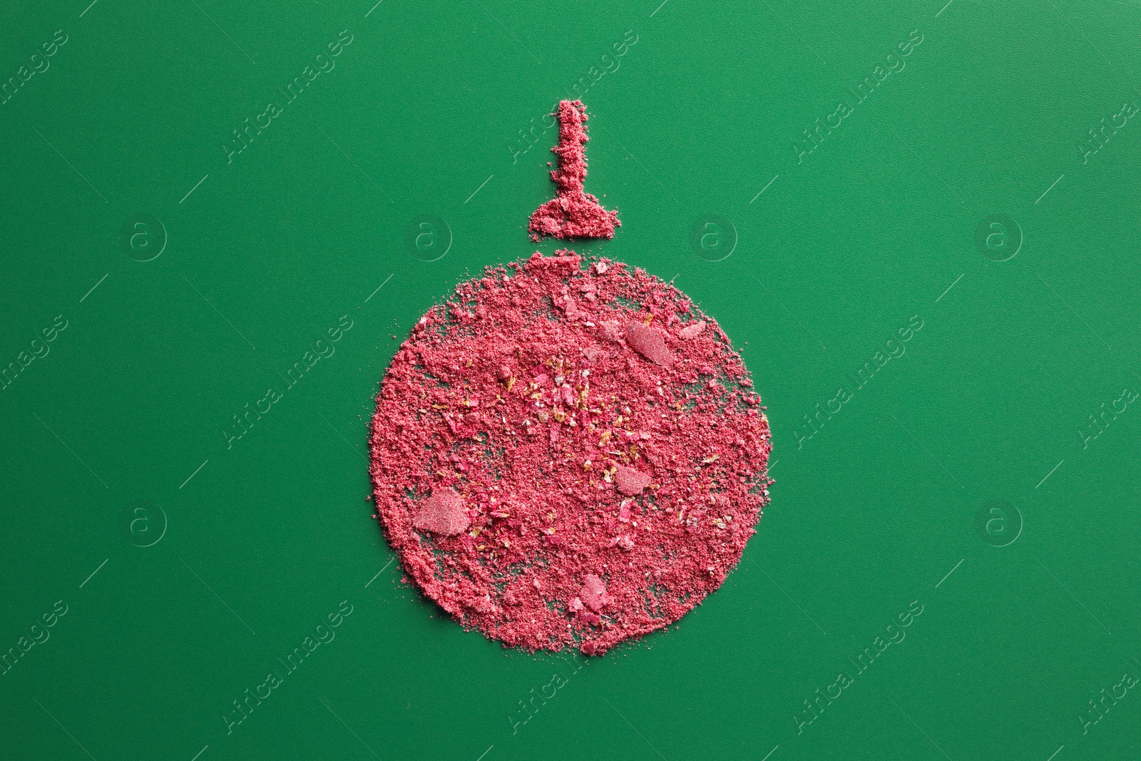 Photo of Christmas ball made of blush on green background, top view