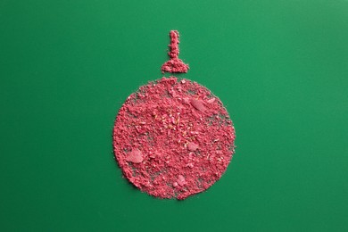 Photo of Christmas ball made of blush on green background, top view