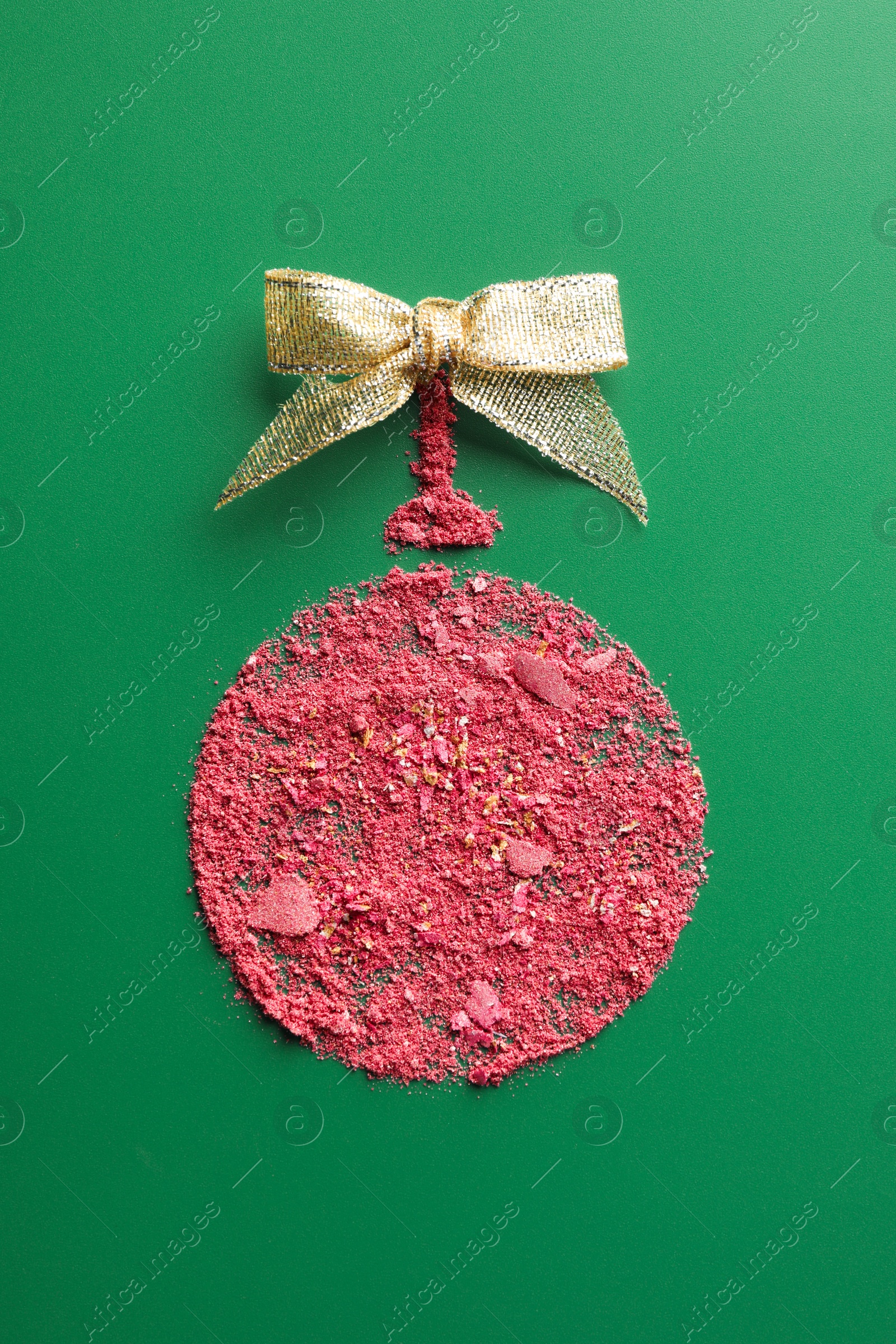 Photo of Christmas ball made of blush and bow on green background, top view