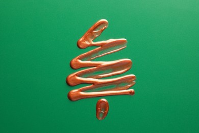 Photo of Christmas tree drawn of cosmetic product on green background, top view