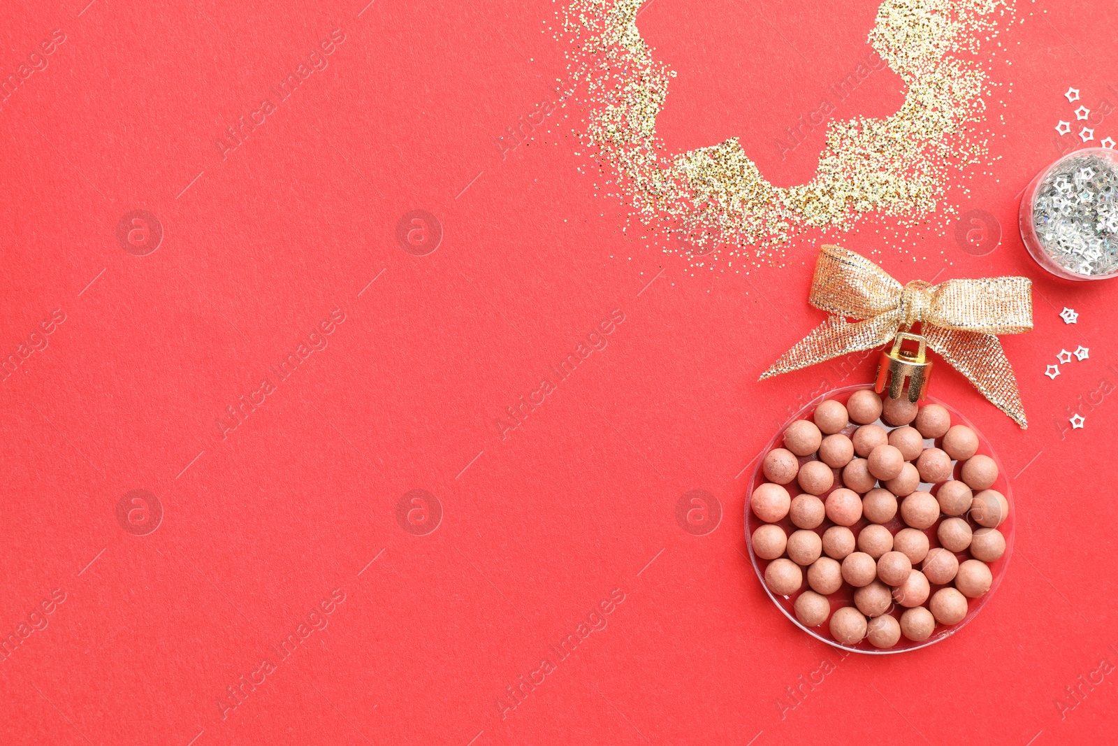 Photo of Christmas ball made with blush and glitter on red background, top view. Space for text