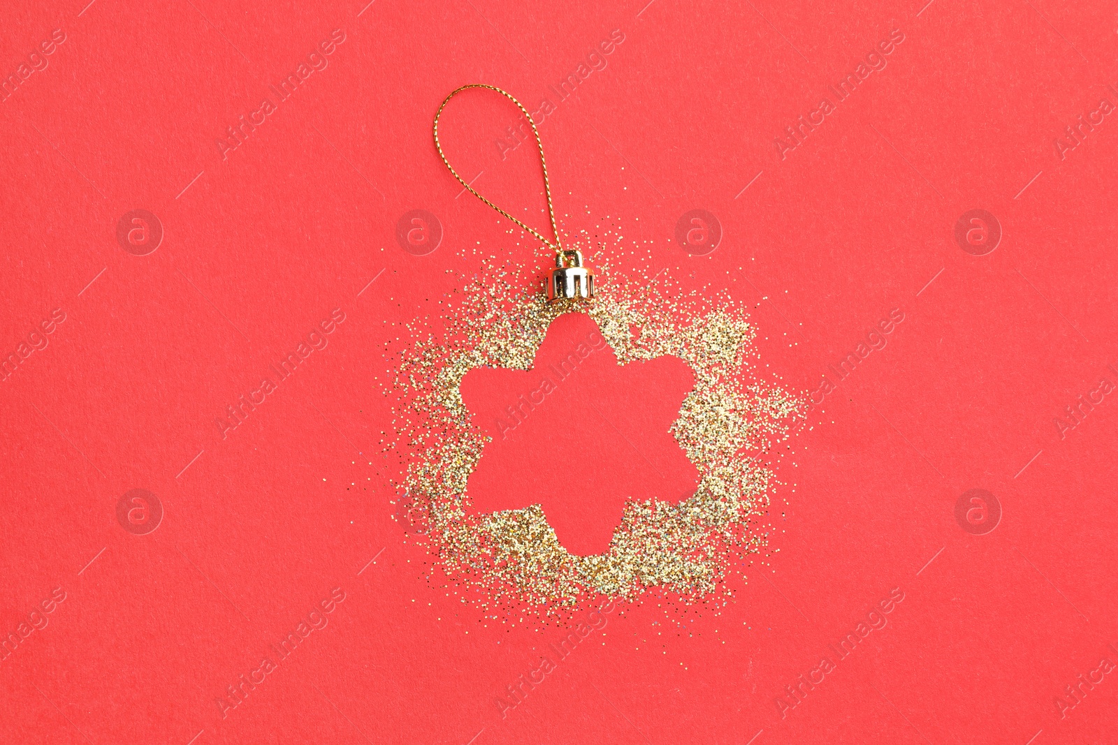 Photo of Christmas ornament made of golden glitter on red background, top view