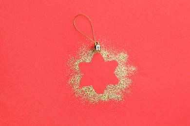 Photo of Christmas ornament made of golden glitter on red background, top view