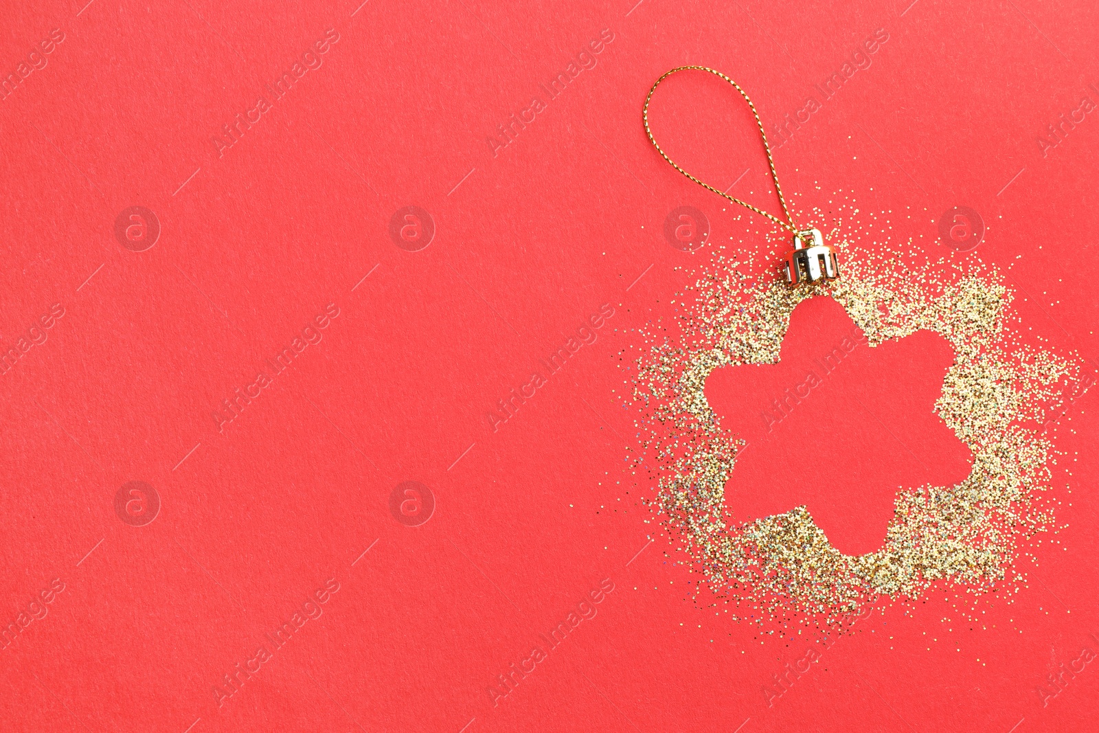 Photo of Christmas ornament made of golden glitter on red background, top view. Space for text