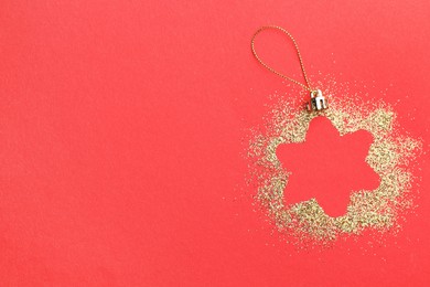 Photo of Christmas ornament made of golden glitter on red background, top view. Space for text