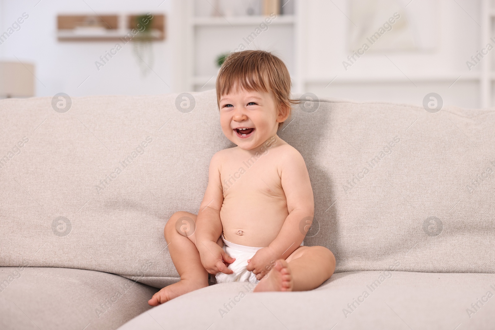 Photo of Little child in diaper on sofa at home