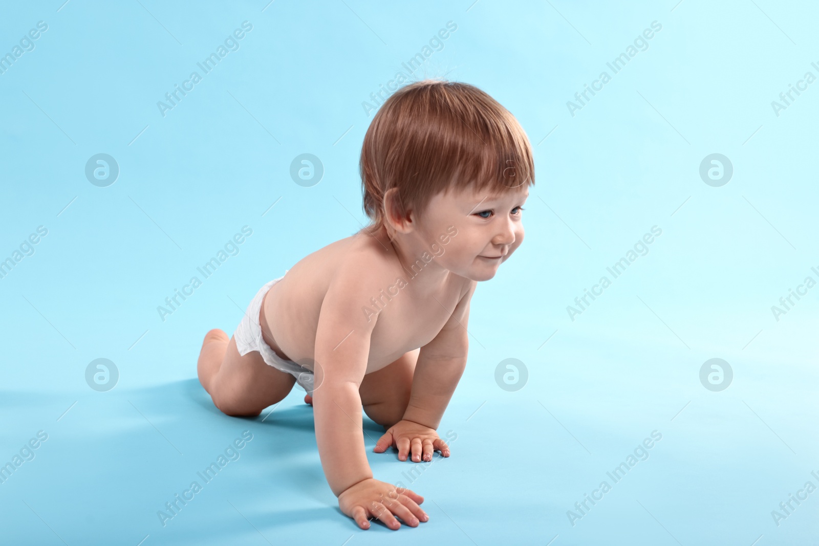 Photo of Cute little child in diaper on light blue background