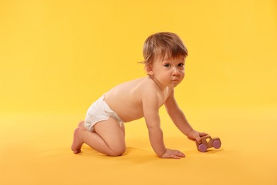 Photo of Little child in diaper with toy on orange background