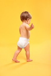 Photo of Little child in diaper on orange background