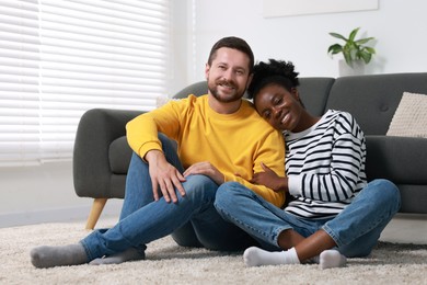 Photo of International relationships. Lovely couple spending time together on floor at home