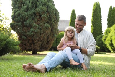 Father and his daughter spending time together on green lawn in park