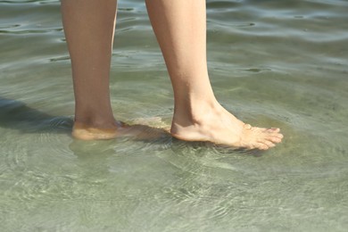 Photo of Woman walking barefoot through water on riverbank, closeup