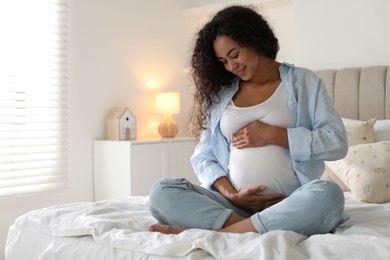 Portrait of beautiful pregnant woman on bed at home