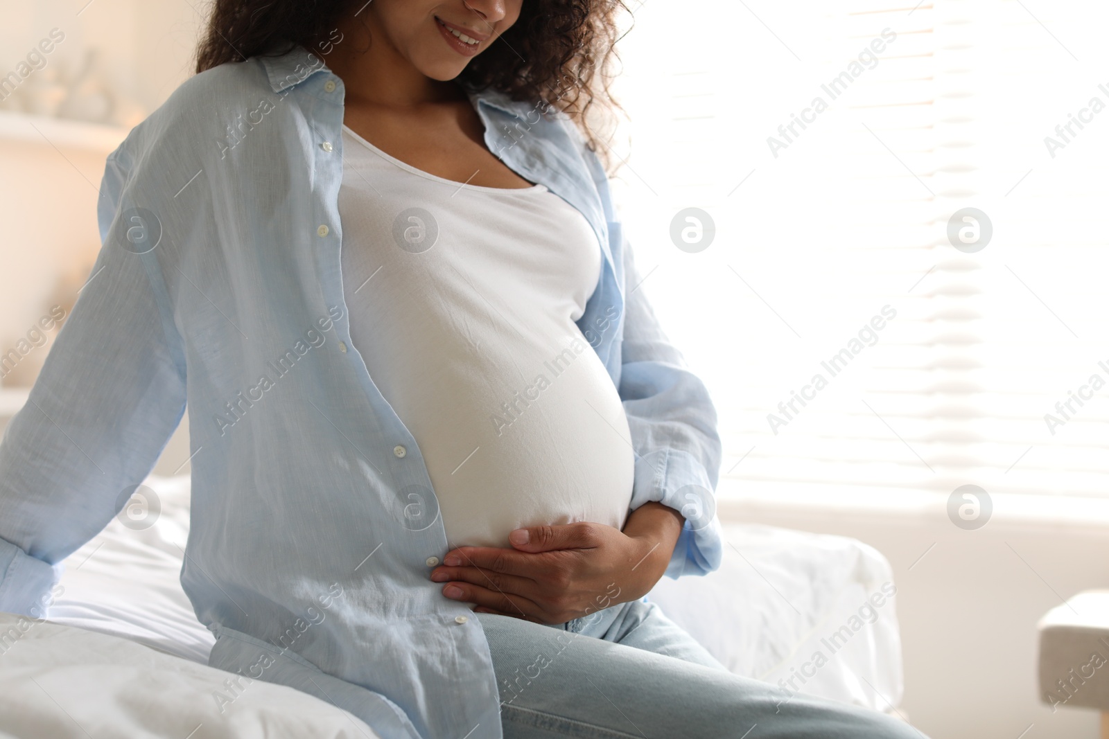 Photo of Pregnant woman on bed at home, closeup