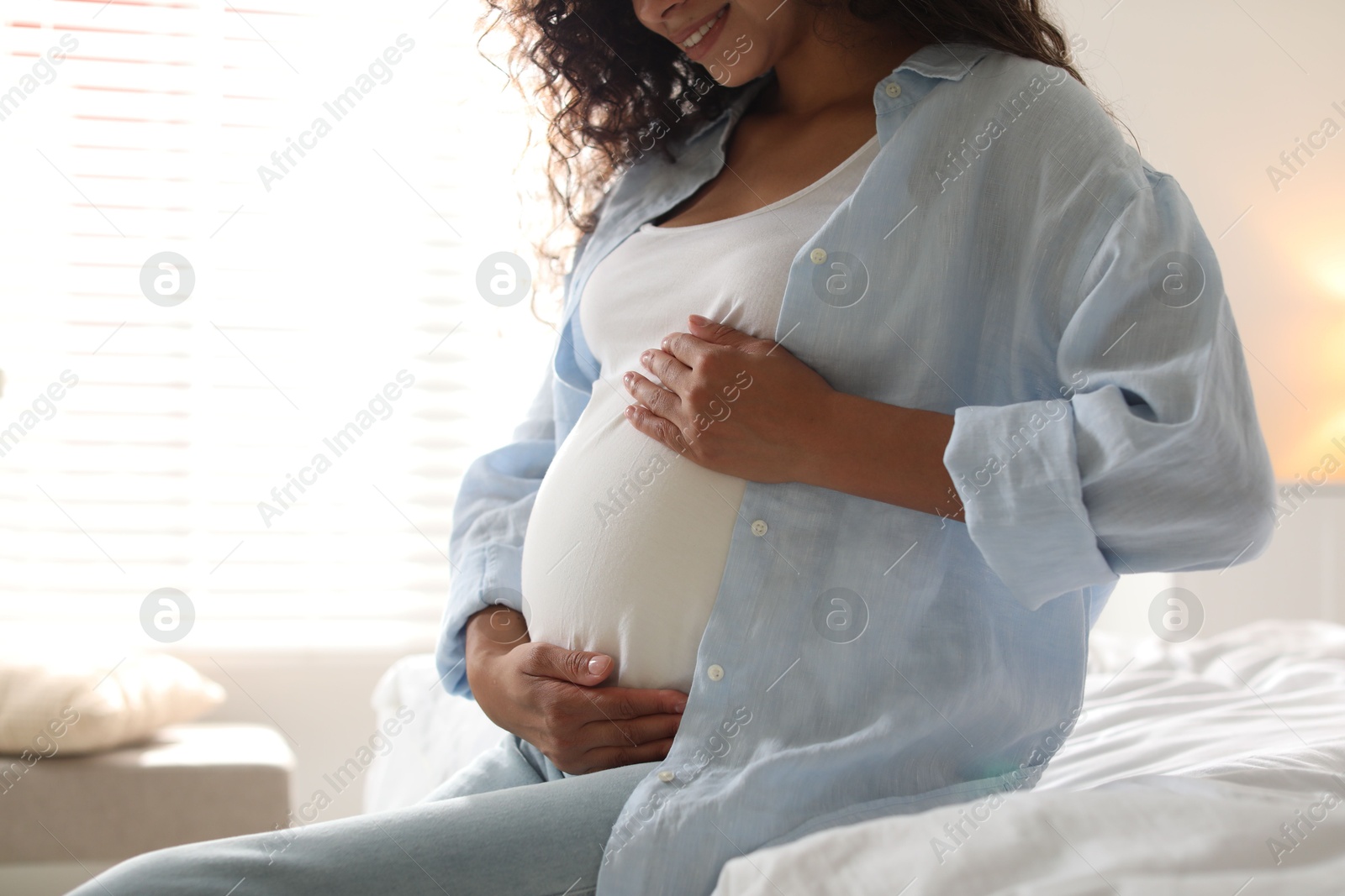 Photo of Pregnant woman on bed at home, closeup