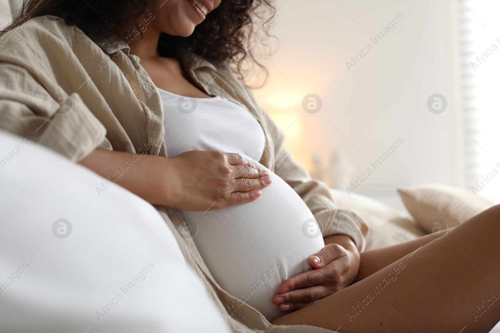 Photo of Pregnant woman on bed at home, closeup