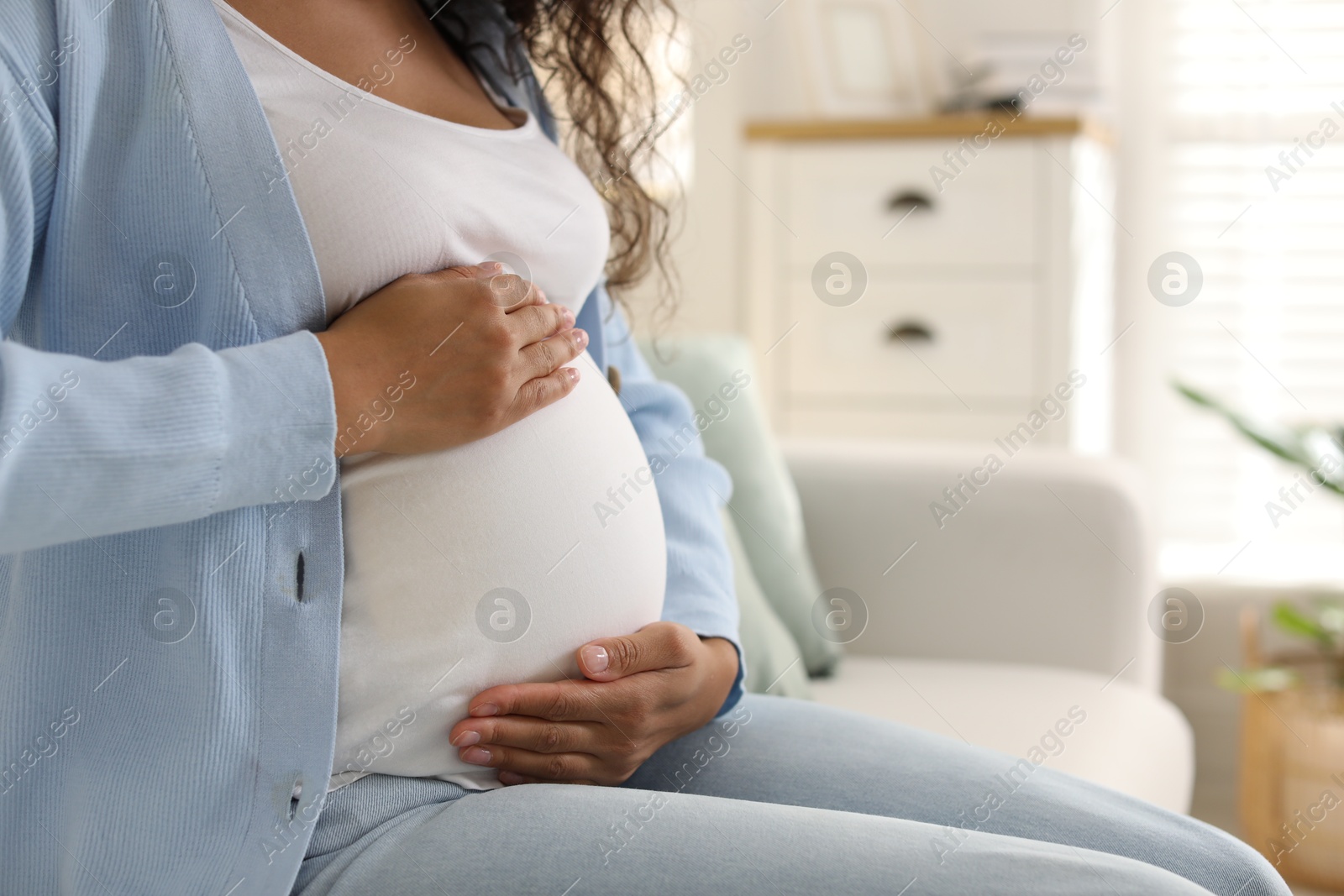 Photo of Pregnant woman on sofa at home, closeup